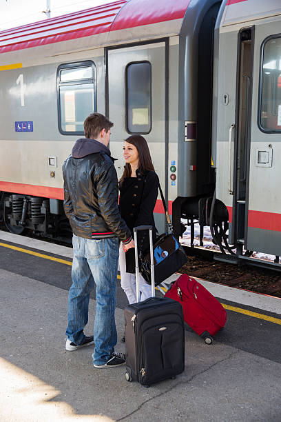 istock Young couple with suitcases waiting for a train...railway station 610013786