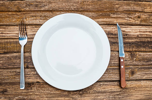 istock Empty plate, fork and knife on wooden background 610013930