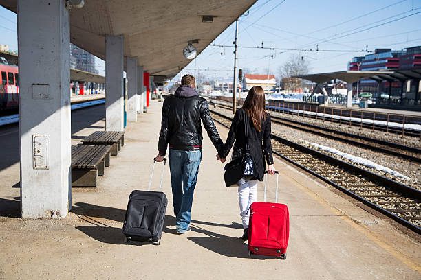 istock Young couple with suitcases waiting for a train...railway station 610014868