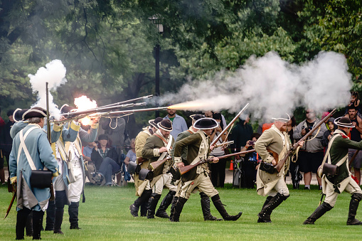 Wheaton, Illinois, USA - September 10, 2016: Congressional soldiers fire muskets while others advance past spectators during mock battle at a reenactment of the American Revolutionary War (1775-1783).