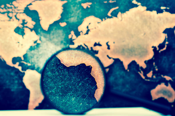 istock Magnifying lens on books against grunge world map 610017274