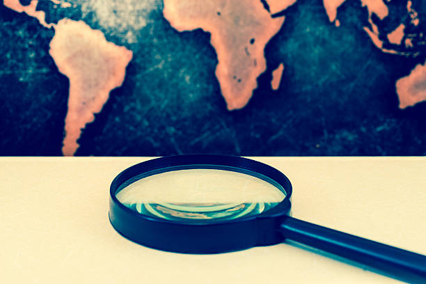 istock Magnifying lens on books against grunge world map 610017330