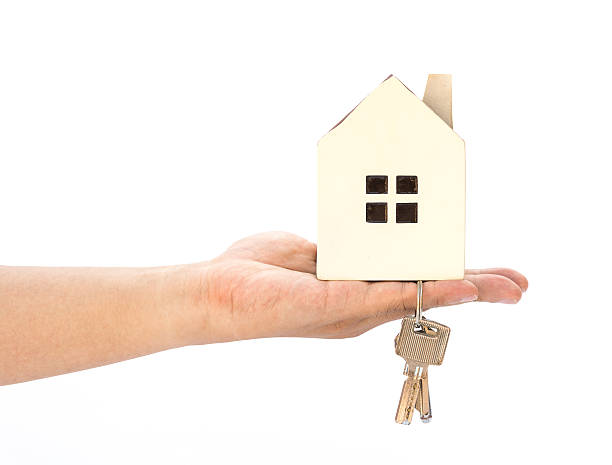 istock hand holding a house model and key on white background 610018400