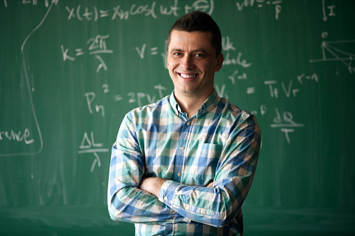 young cheerful professor in front of blackboard