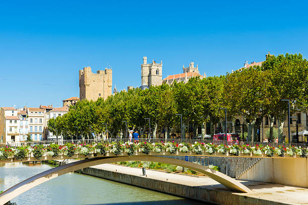 Narbonne cathedral and town hall in background Narbonne, France - August 8, 2016: Narbonne cathedral and town hall in background. Canal de la Robine with footbridge in front. narbonne stock pictures, royalty-free photos & images