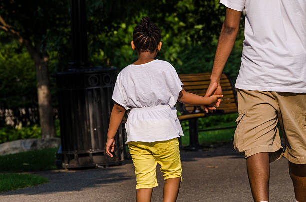 Ottawa, Canada - July 24, 2014: Young girl holding hands with father walking in downtown park