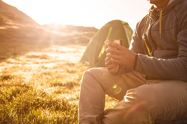 istock Young man drinking tea at sunrise in mountains. 610032614