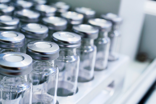 Glass vials for liquid samples. Laboratory equipment for dispensing fluid samples. Shallow depth of field.