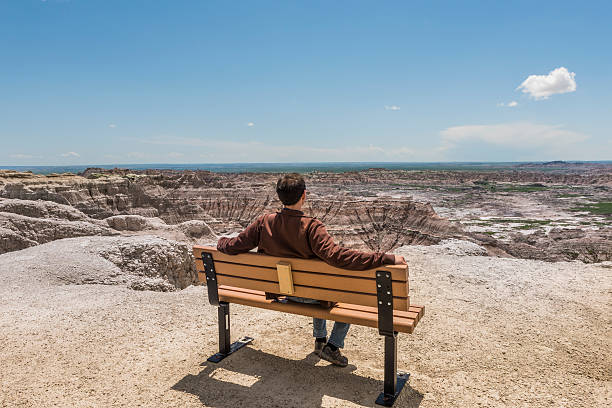 homem sentado no banco olhando para cânions badlands erodidos - bench mountain park sitting - fotografias e filmes do acervo
