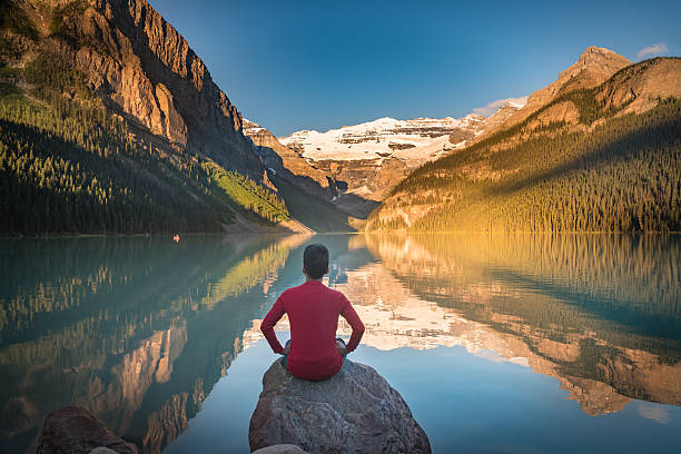 istock Man sit on rock watching Lake Louise reflections 610033690