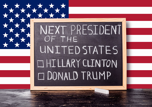 American election concept with flag and handwriting text next president of United States Donald Trump Hillary Clinton written in chalkboard background, close up