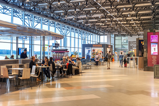 Milan, Italy - September 22, 2015: People sitting in cafe and walking inside Terminal 2 currently used by EasyJet in Milan Malpensa Airport -  largest airport in northern Italy and currently the 28th busiest airport in Europe.