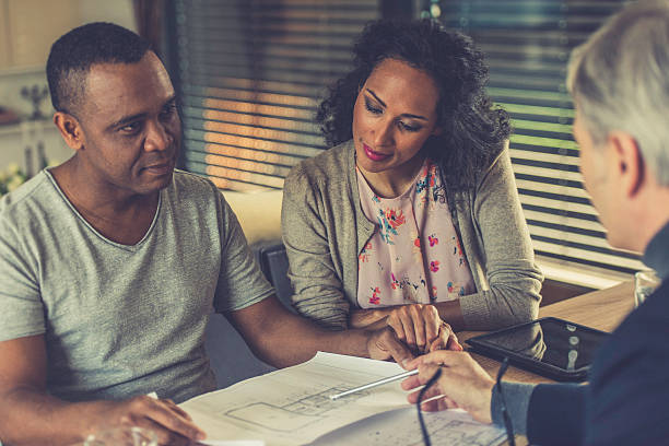 istock Couple looking at blueprints and talking with an architect 610038990