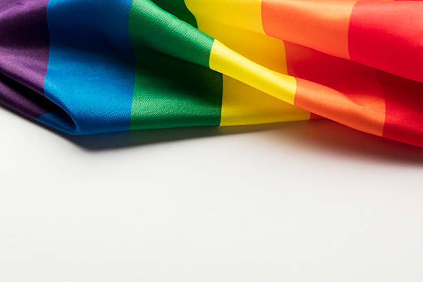 Gay pride rainbow flag on a plain background Photograph of the LGBT rainbow flag, lesbian, gay, bisexual and transgender on a plain background pride flag stock pictures, royalty-free photos & images
