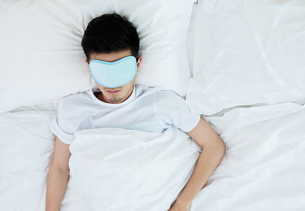 istock Young man wearing sleep mask on bed 610045822