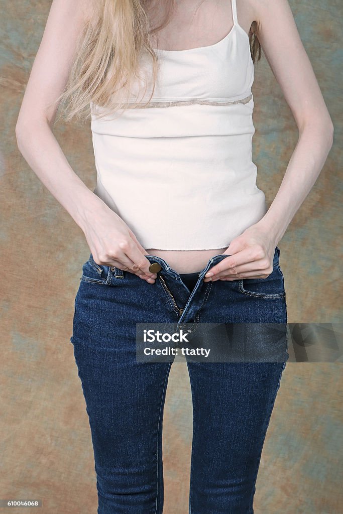 Zipping up tight jeans Young girl trying to zip up tight blue jeans Narrow Stock Photo