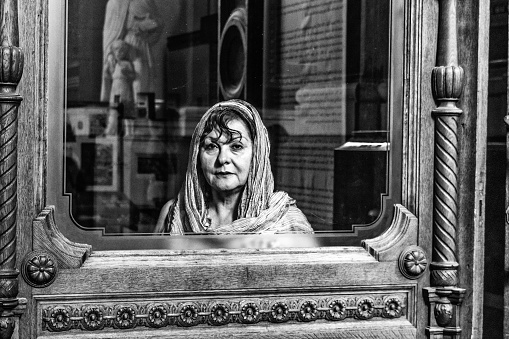 Sad mature hispanic woman in window