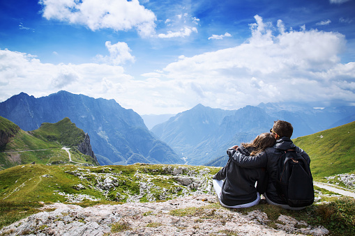 Couple of travelers (hikers) on top of a mountain enjoying valley view. Mangart is a mountain in the Julian Alps, located between Italy and Slovenia. Travel, Holidays, Freedom and Lifestyle Concept
