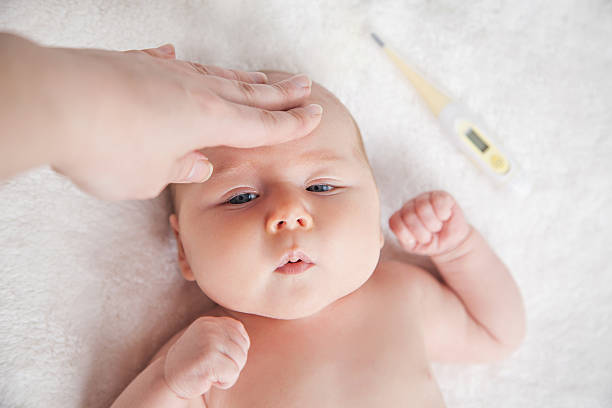 mother checks the temperature of a sick baby - child fever illness thermometer imagens e fotografias de stock