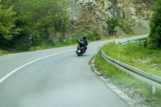 istock Biker riding scooter on an mountain road 610051116