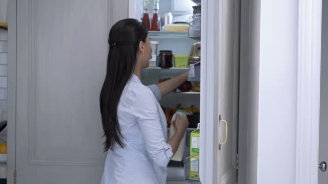 Healthy woman at home taking groceries from the fridge