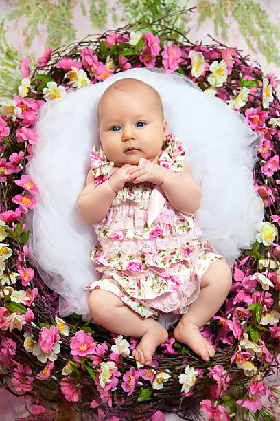 petite fille menteuse dans un nid de fleurs - newborn little girls baby lying down photos et images de collection