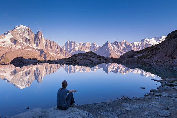 femme regardant la chaîne de montagnes des alpes et beau reflet dans le lac - european alps women summer outdoor pursuit photos et images de collection