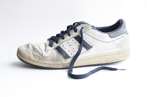 Clean, isolated shot of the side of an old sports shoe, in heavily worn condition.