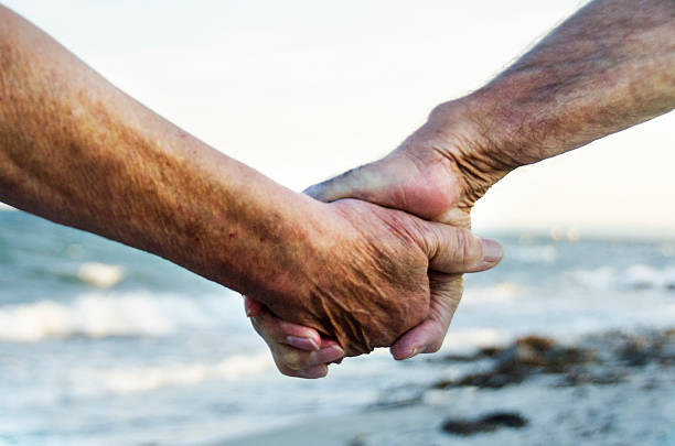 istock Old mann and woman holding hands after sea bathing 610125564
