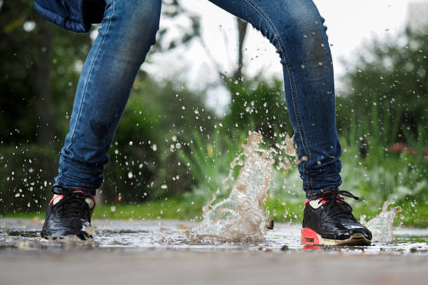 istock Human Legs in jeans and sneakers in a puddle. 610126912