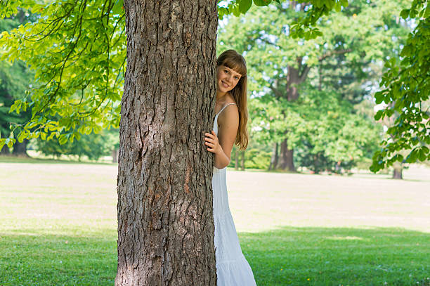 istock Young attractive woman hiding behind a tree 610127308
