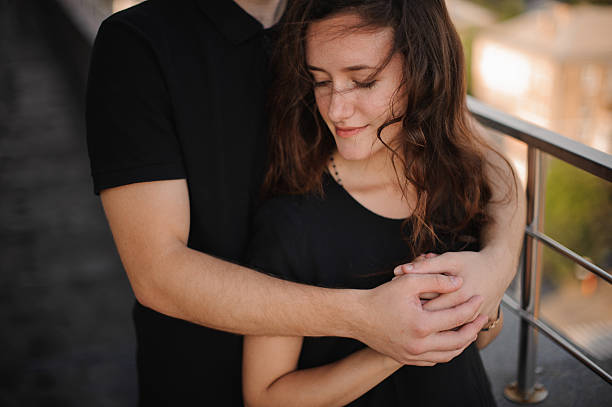 istock Young loving couple outdoors hugging and looking away 610130748