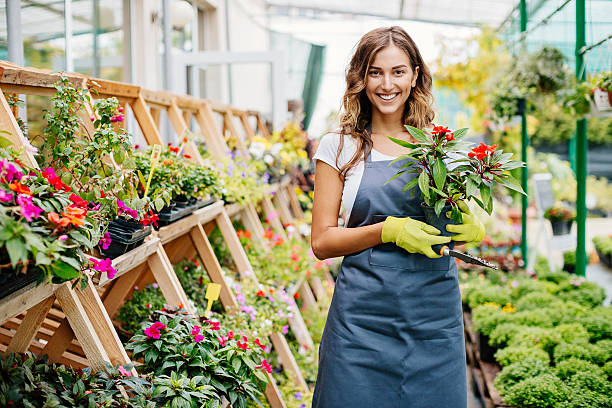 Smiling young gardener Attractive young woman in a flower center. farm produce storage stock pictures, royalty-free photos & images
