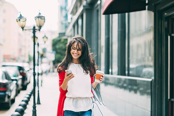 heureuse jeune femme en texto dans la rue - red text messaging cafe teenage girls photos et images de collection