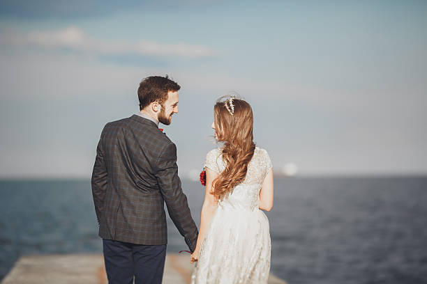 istock Married wedding couple standing on a wharf over the sea 610132142
