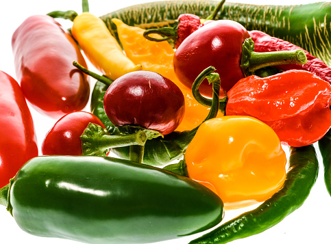 Different variety of hot peppers - a bunch of chilies, isolated on white. Hot pepper Macedonian Fringed, Sarit Gat, Red Cherry, Cayenne, Serrano, Habanero Orange, Jalapeno, Fatalii Yellow, Trinidad Scorpion Moruga and regular chili.