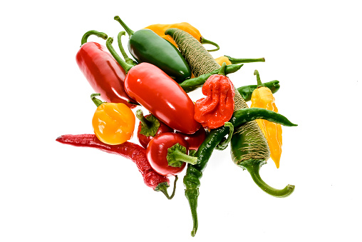 Different variety of hot peppers - a bunch of chilies, isolated on white. Hot pepper Macedonian Fringed, Sarit Gat, Red Cherry, Cayenne, Serrano, Habanero Orange, Jalapeno, Fatalii Yellow, Trinidad Scorpion Moruga and regular chili.