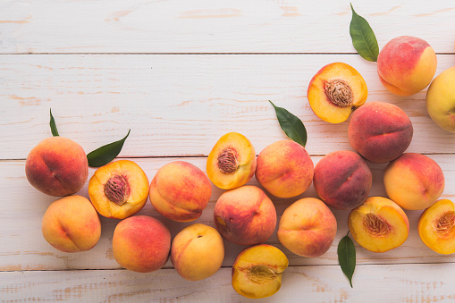 a lot of fresh peaches on a white table