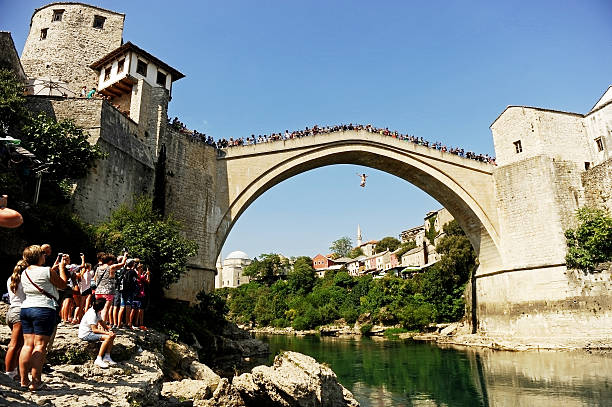High diving into Neretva river in Mostar Mostar, Bosnia and Herzegovina - August 29, 2015: Tourists watch a high diver jumping from the old bridge of Mostar into Neretva river. stari most mostar stock pictures, royalty-free photos & images