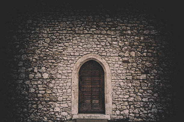 Dark doorway A wooden door in an old stone building. old stone wall stock pictures, royalty-free photos & images