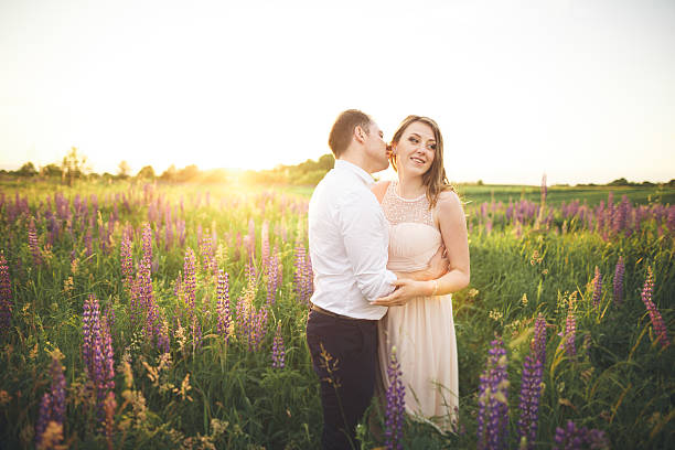 istock Young wedding couple walking on field with flowers 610138360