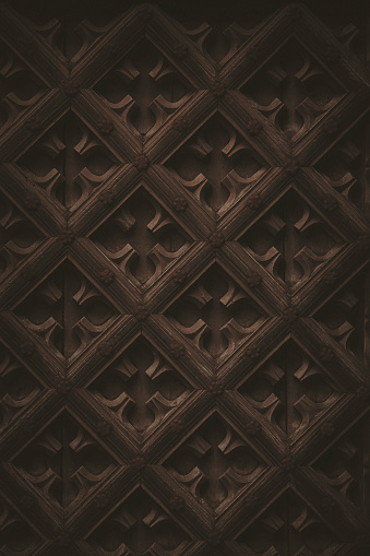 Dark, low key wooden shapes and pattern from the exterior of a 16th century church door.