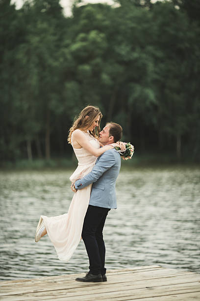 istock Groom carrying bride near lake and forest 610141156
