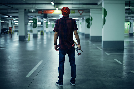 Rear view of skateboarder holding his longboard.