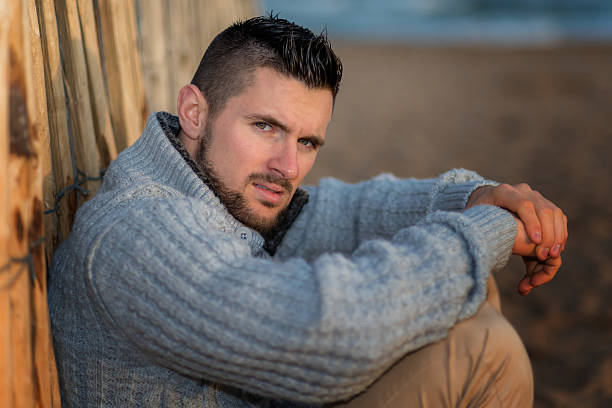 istock Man sitting by fence on a beach 610141884