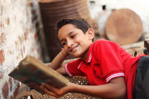 Rural little school student reading a story book. 