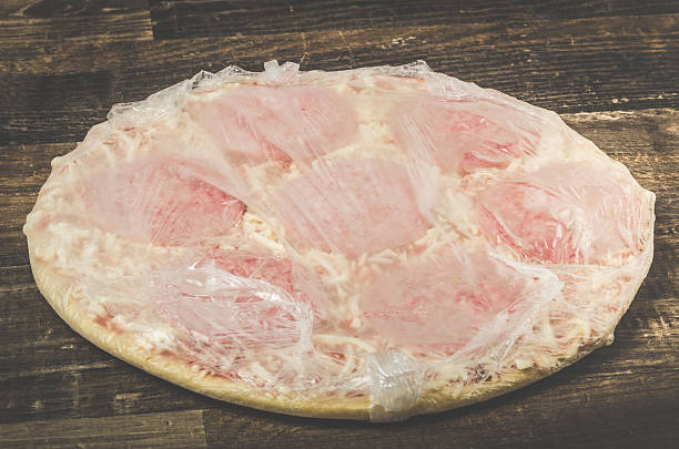 istock Delicious mouth watering raw frozen pizza on a kitchen table 610143906