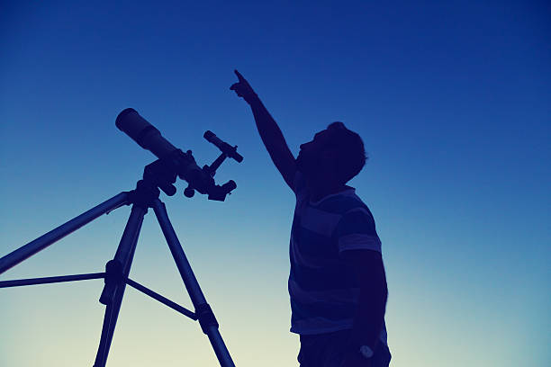 istock Man looking at the night sky with telescope beside him. 610145360