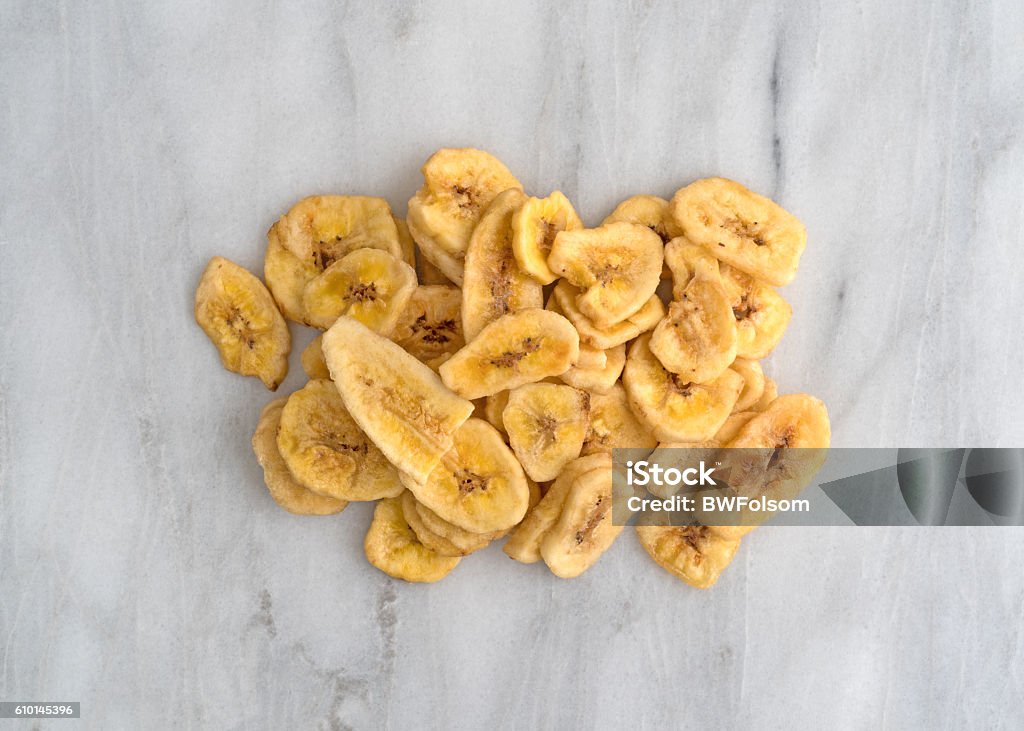 Dried bananas on a marble cutting board Top view of dehydrated banana chips on a gray marble cutting board. Banana Chip Stock Photo