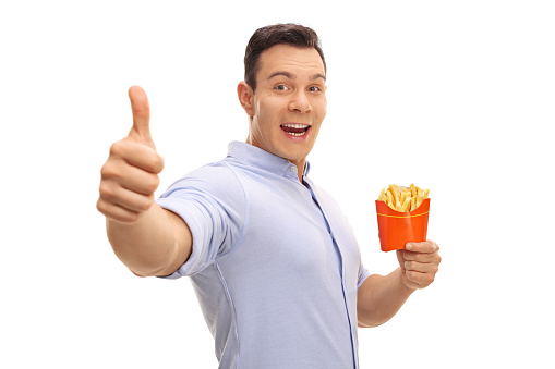 Happy man holding a bag of fries and giving a thumb up isolated on white background